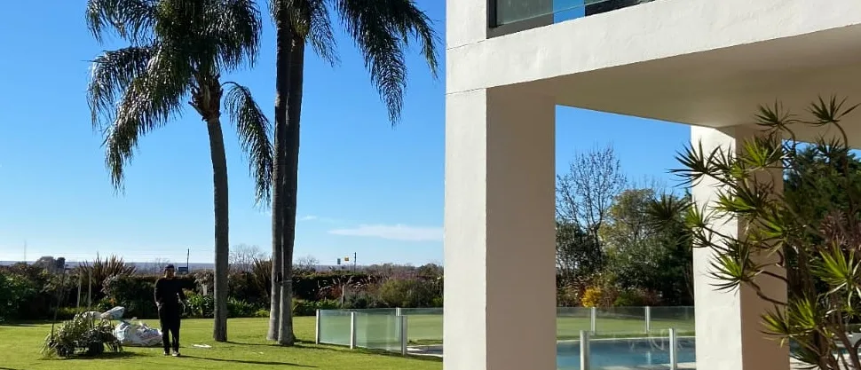 Jardín con arquitectura moderna, palmeras y césped amplio